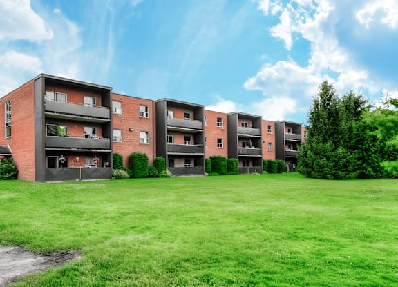 A row of red brick apartment buildings with green grass in front.