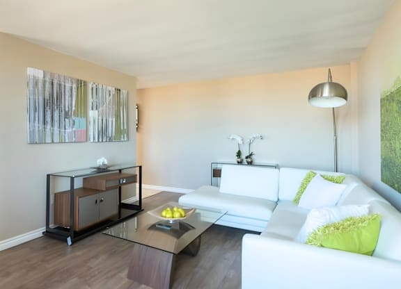 A modern living room with a white couch and a glass coffee table.