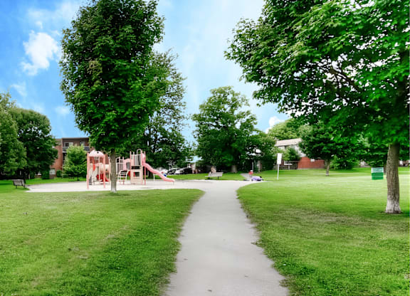 A playground with a slide is in the middle of a grassy area.