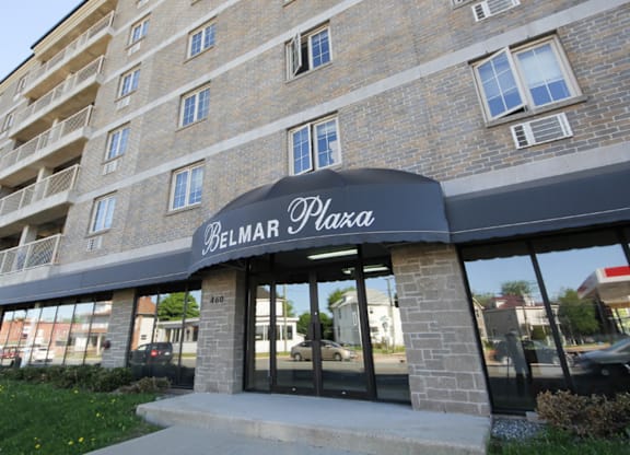 The Belmar Plaza building is a multi-story brick structure with a black awning.