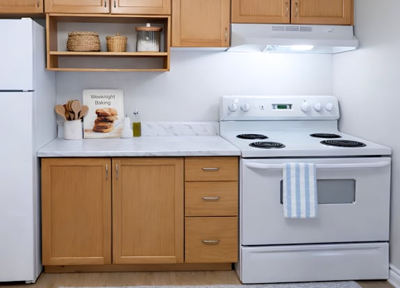 A kitchen with a white stove and wooden cabinets.