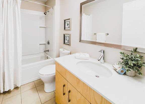 A bathroom with a white toilet, a white sink, and a white shower curtain.