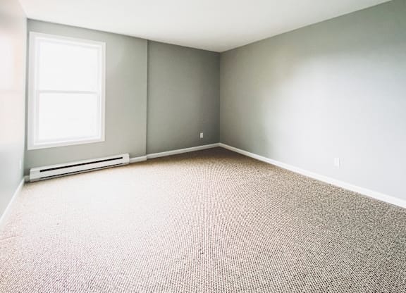 A room with a window and a carpeted floor.