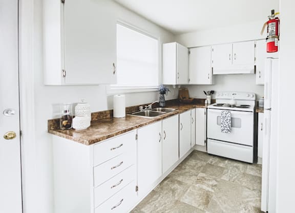 A kitchen with white cabinets and a white stove.