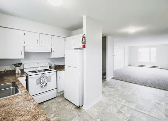 A kitchen with white appliances and a granite counter.