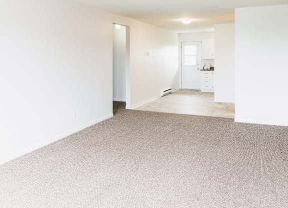 A room with a carpeted floor and a doorway leading to another room.
