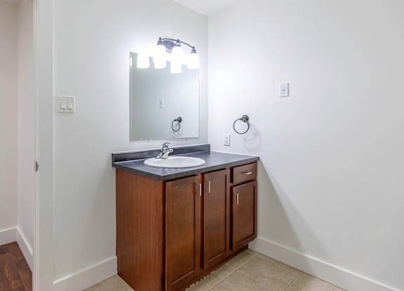 A bathroom with a sink, mirror, and lighting fixture.