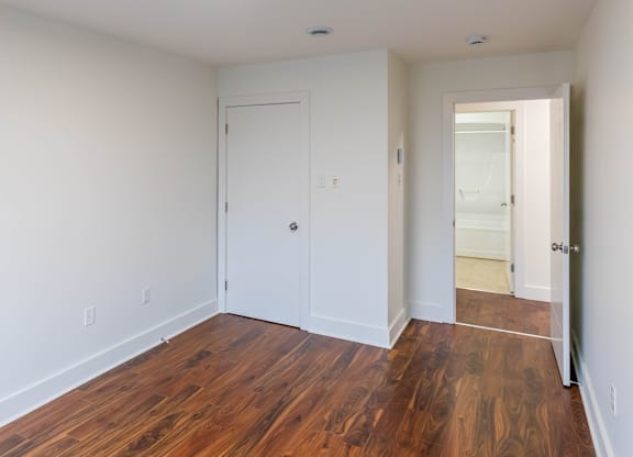 A room with a white door and a wooden floor.