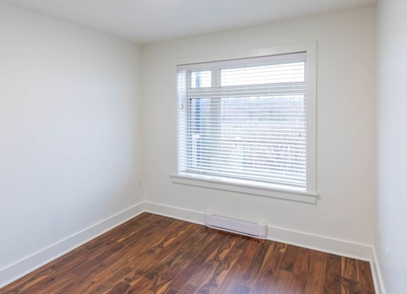 A room with a window and wooden flooring.