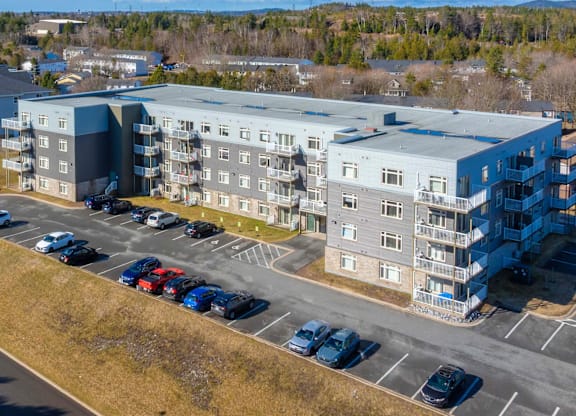 A large apartment complex with a parking lot in front.