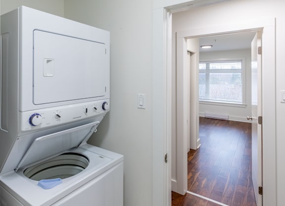 A white oven with a door open is in a room with a wooden floor.