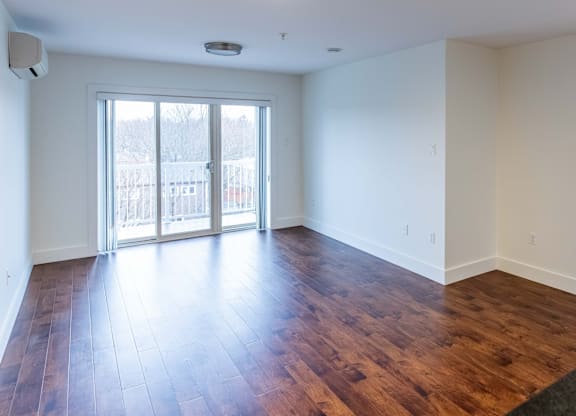 A room with a sliding glass door and wood flooring.