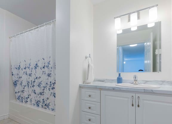 A bathroom with a white shower curtain and a white counter top.