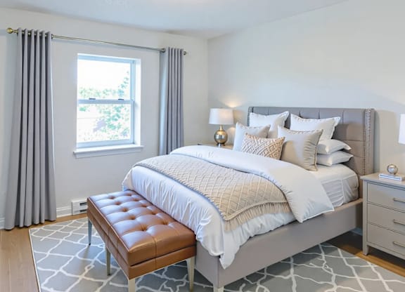 A bedroom with a large bed and a bench in front of it.