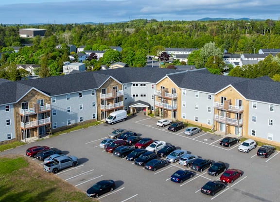 A parking lot with cars and apartment buildings in the background.