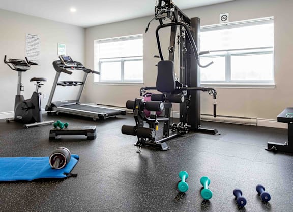 A gym with a variety of equipment including treadmills, elliptical machines, and weights.