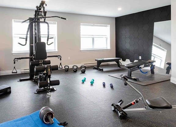 A home gym with a variety of equipment including a stationary bike, a rowing machine, and dumbbells.