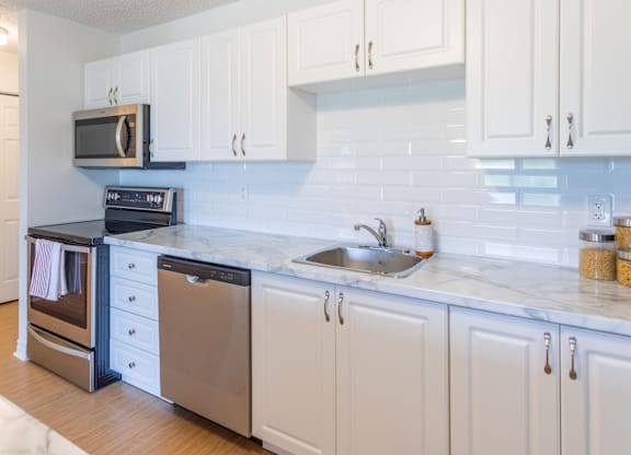 A kitchen with white cabinets and a marble countertop.