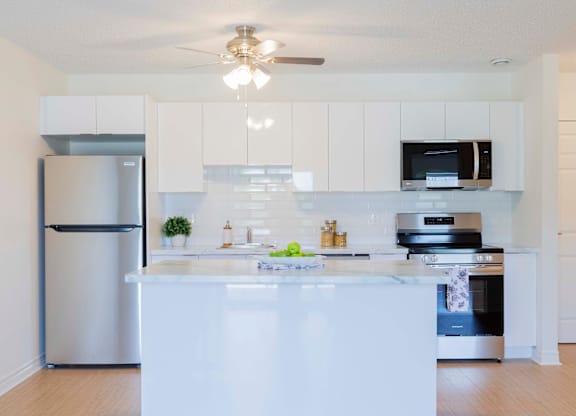 A modern kitchen with a white island and stainless steel appliances.