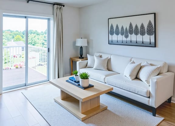 A living room with a white couch, a wooden coffee table, and a painting on the wall.