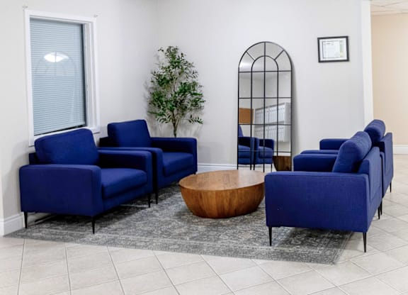 A living room with blue chairs and a wooden coffee table.