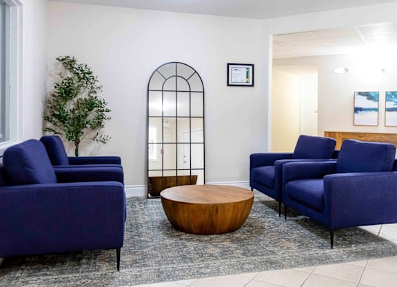 A living room with blue chairs and a wooden coffee table.