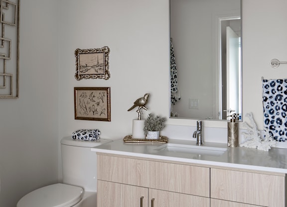 A bathroom with a toilet, sink, and mirror.
