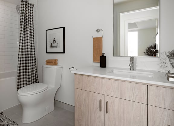 A bathroom with a toilet, sink, and a mirror.