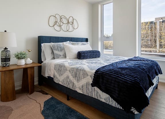 A bedroom with a large bed and a blue rug.