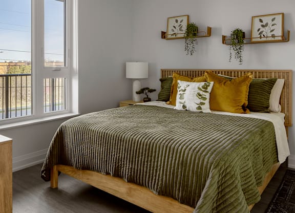 A bedroom with a bed, a lamp, and two wall shelves with plants.