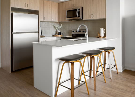 A kitchen with a white counter and wooden cabinets.