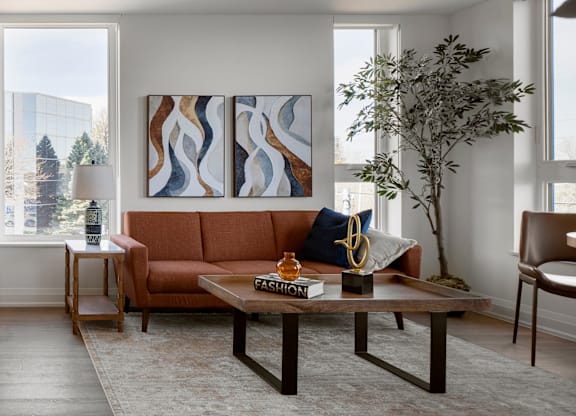 A living room with a brown couch, a coffee table, and a large painting on the wall.