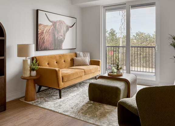 A living room with a tan couch and a large painting of a bull on the wall.