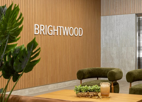 A room with a wooden table and green chairs with the word "Brightwood" on the wall.