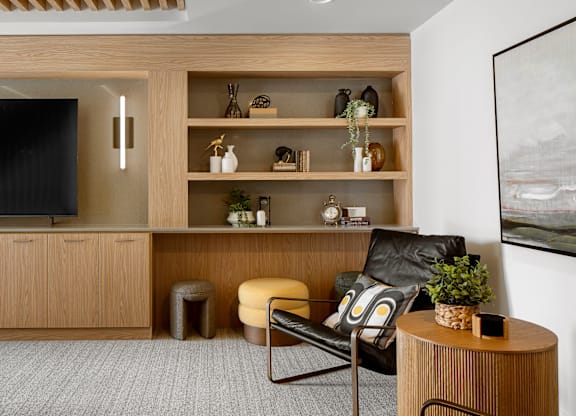 A modern living room with a black leather chair and a wooden cabinet.