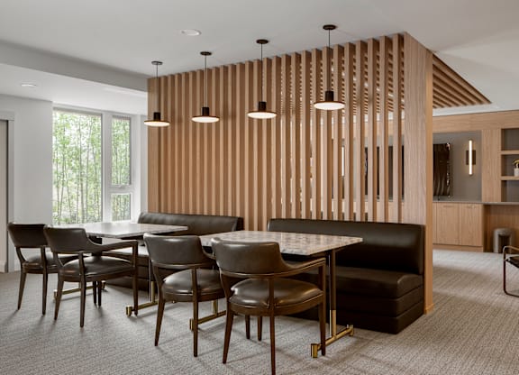 A modern dining room with a wooden partition and a black sofa.