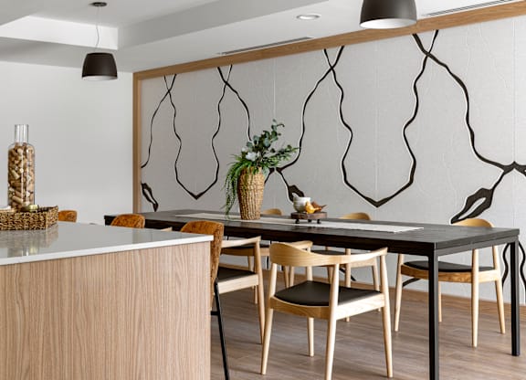 A modern dining room with a black table and wooden chairs.