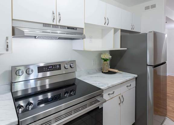 A modern kitchen with a stainless steel oven and white cabinets.