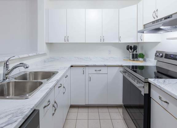 A kitchen with white cabinets and a marble countertop.