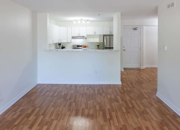 A kitchen with white cabinets and a wooden floor.