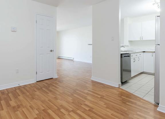 A kitchen with white cabinets and a wooden floor.