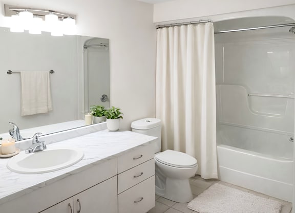 A white bathroom with a sink, toilet, and shower.