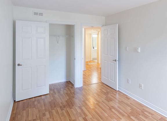 A room with white walls and wooden flooring with two white doors.