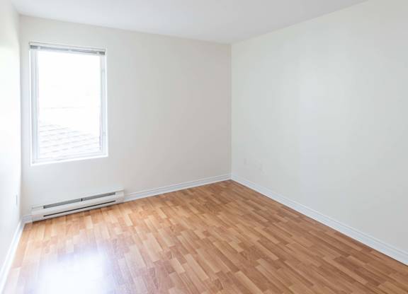 A room with wooden flooring and a window.