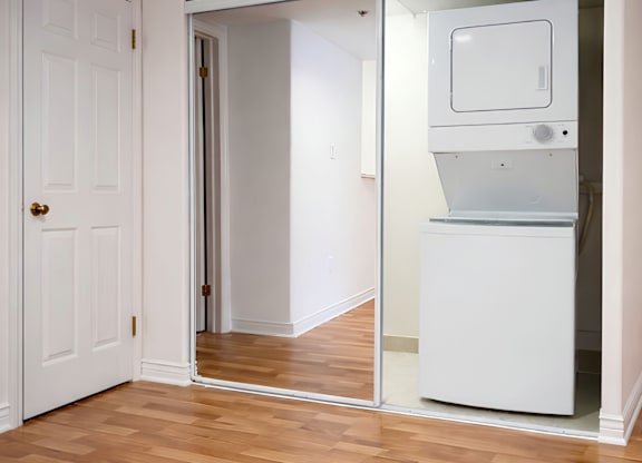 A white door is open to a room with a white fridge.