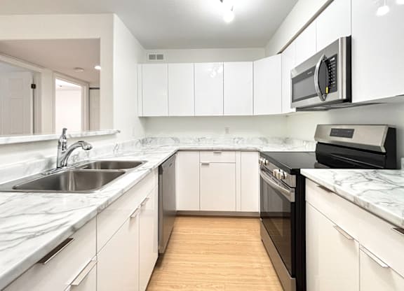 A kitchen with white cabinets and a marble countertop.