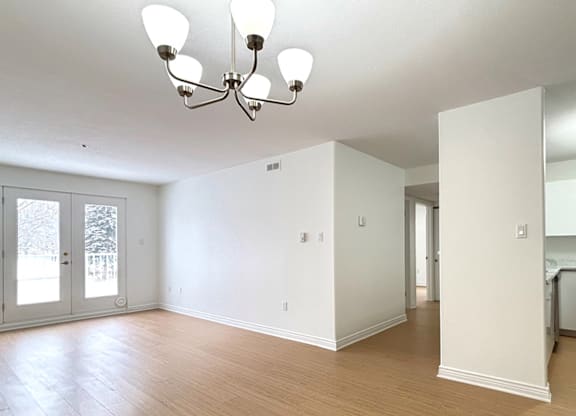 A large empty room with a chandelier and wood flooring.