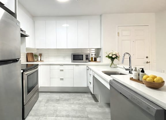 A modern kitchen with white cabinets and stainless steel appliances.