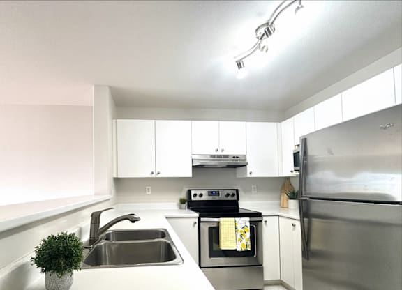 A modern kitchen with stainless steel appliances and white cabinetry.