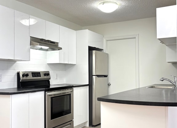 A kitchen with white cabinets and a black countertop.